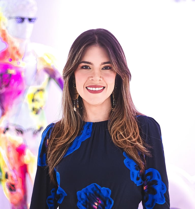 Natalia Devia sonriendo, con vestido azul de flores, frente a arte colorido